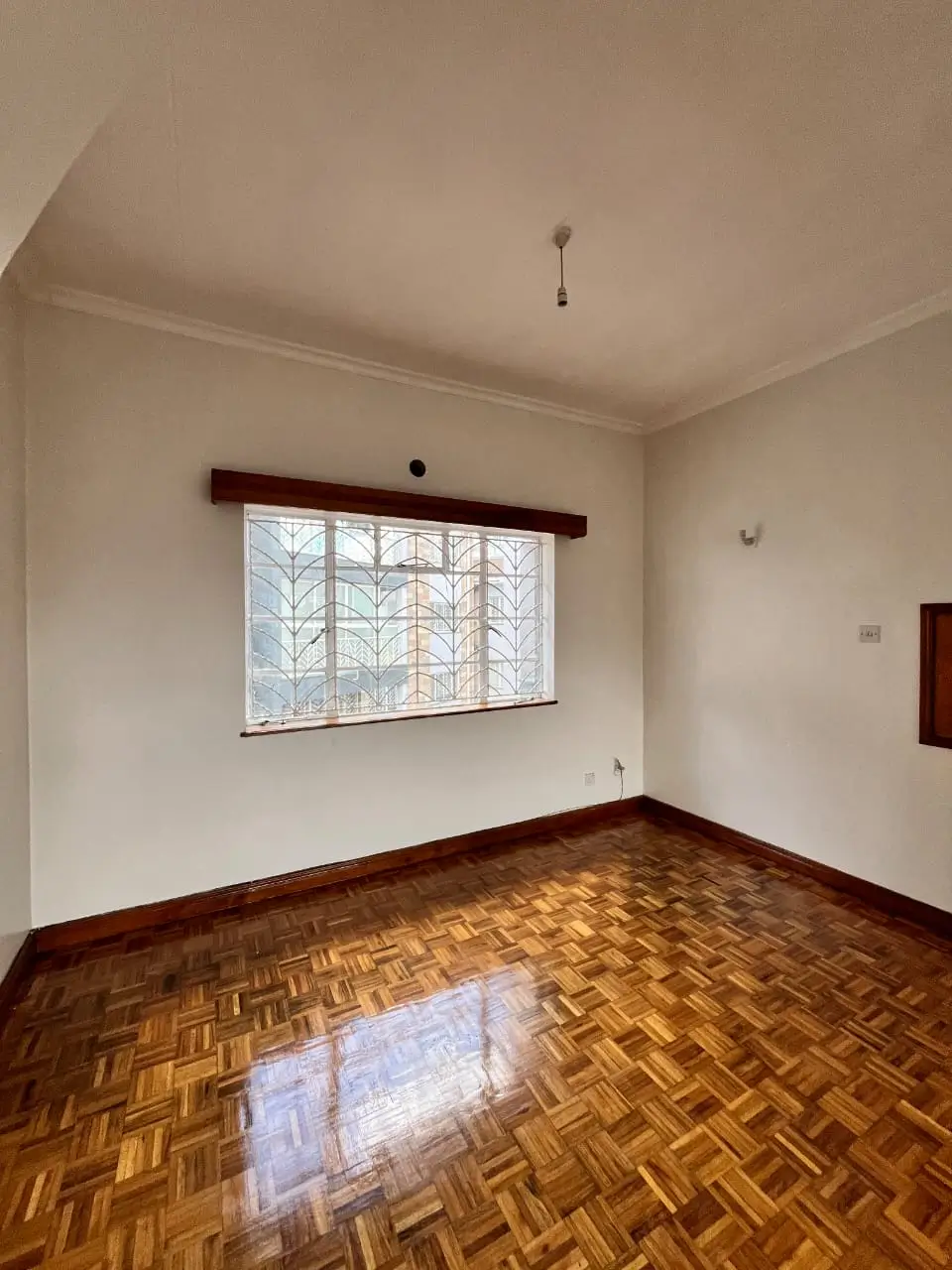 Bright bedroom with herringbone wood flooring and large window
