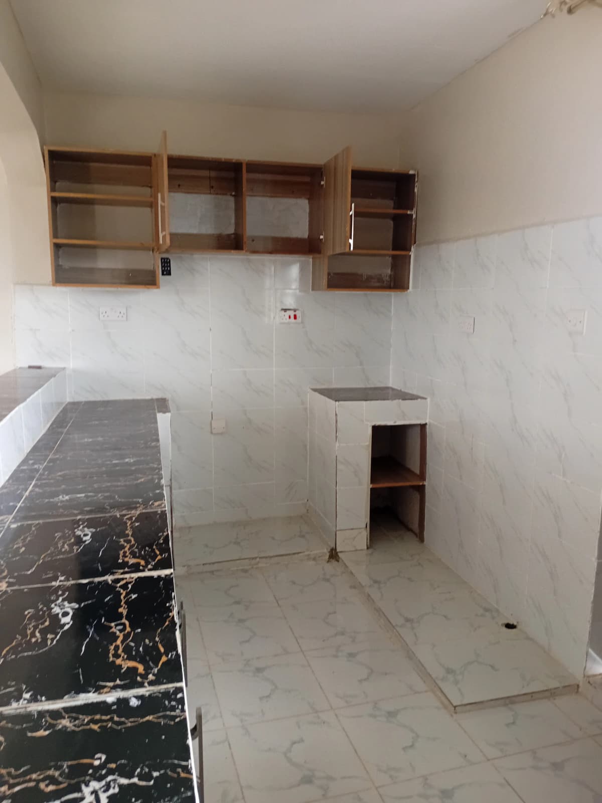 Bare kitchen with marble countertop and open wooden cabinets