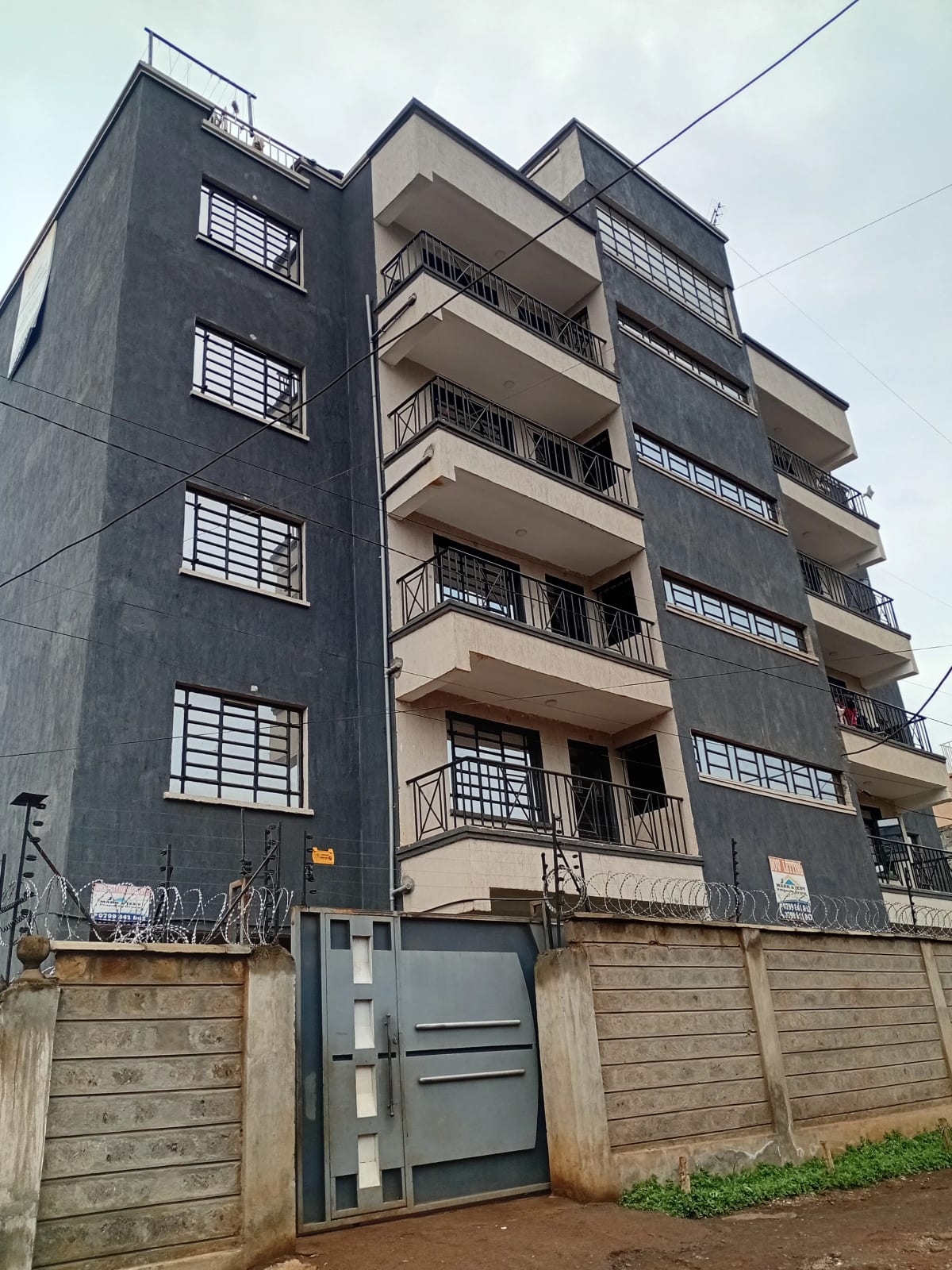 Modern multi-story apartment building with balconies and gate