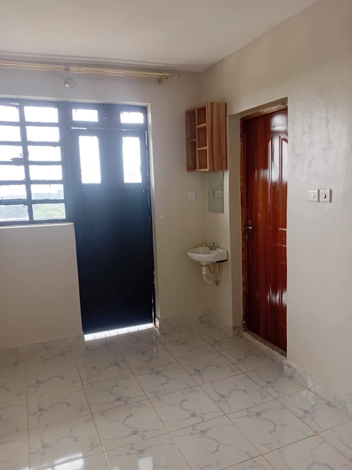 Bright entrance lobby with tiled flooring and red wooden doors