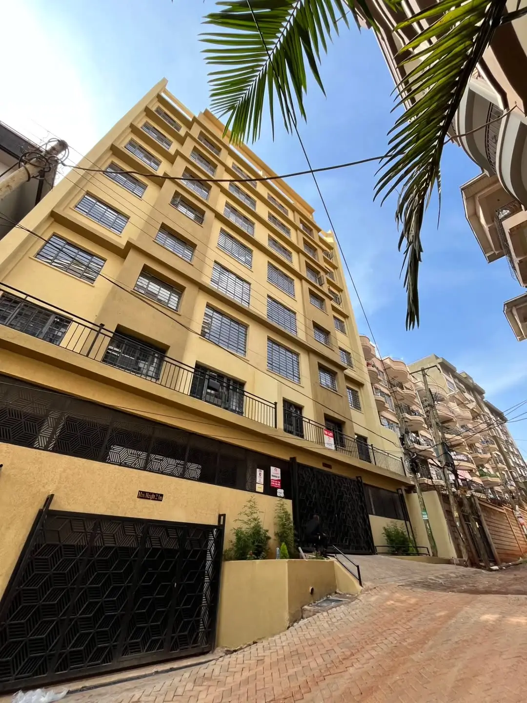 Modern yellow residential building facade with palm trees