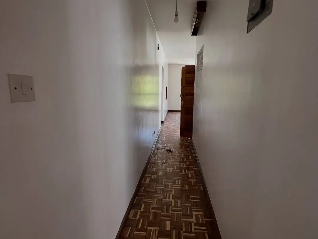 Narrow hallway with wooden herringbone flooring and white walls