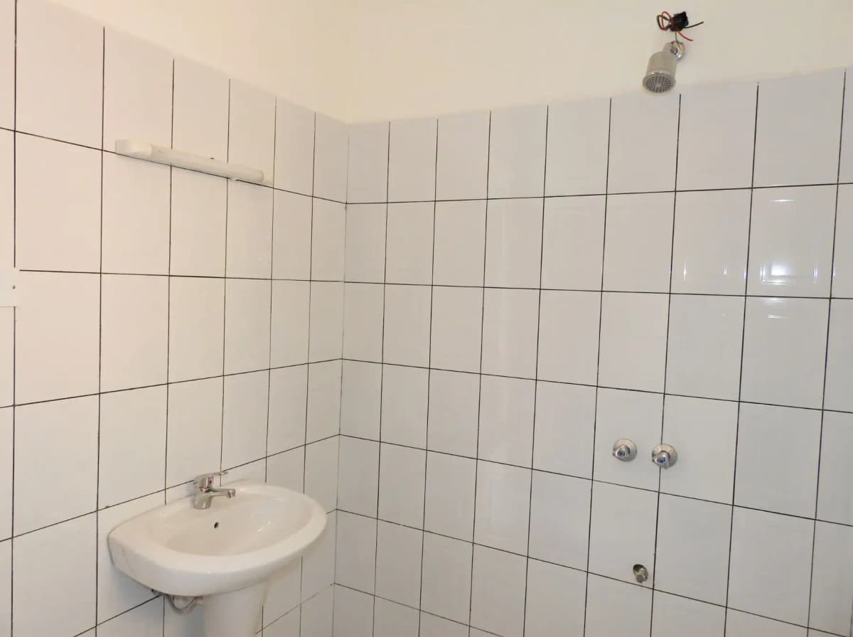 Compact bathroom with white tile walls and wall-mounted sink