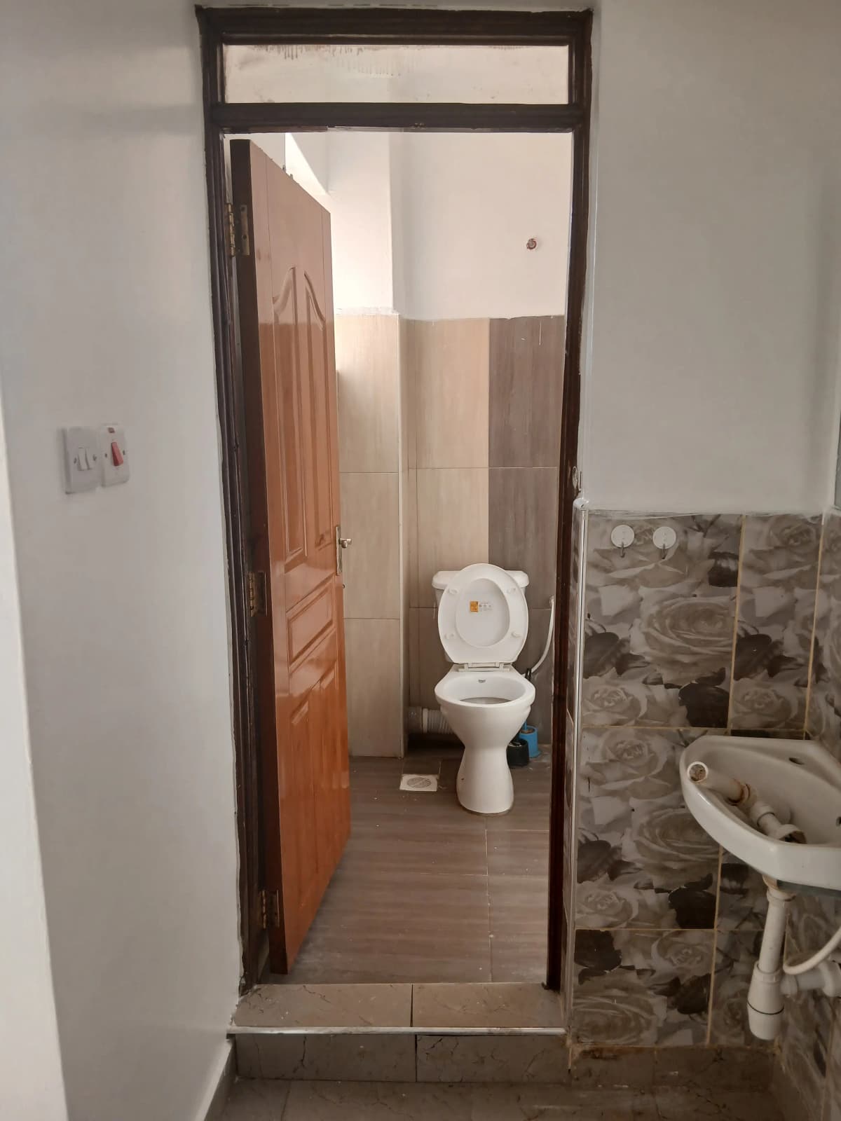 Compact bathroom with toilet, sink, and tiled walls