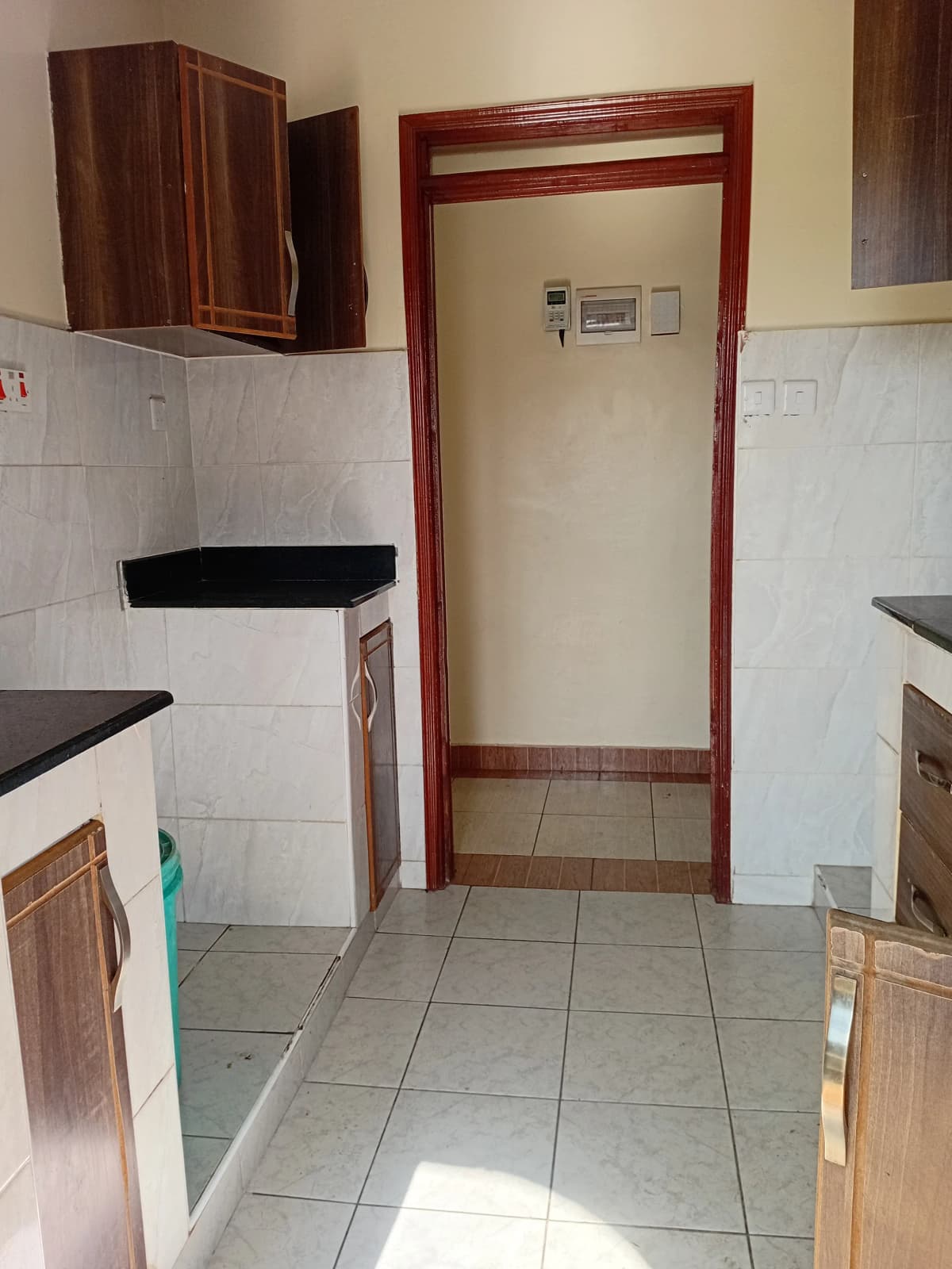Compact kitchen with tile flooring and wooden cabinetry