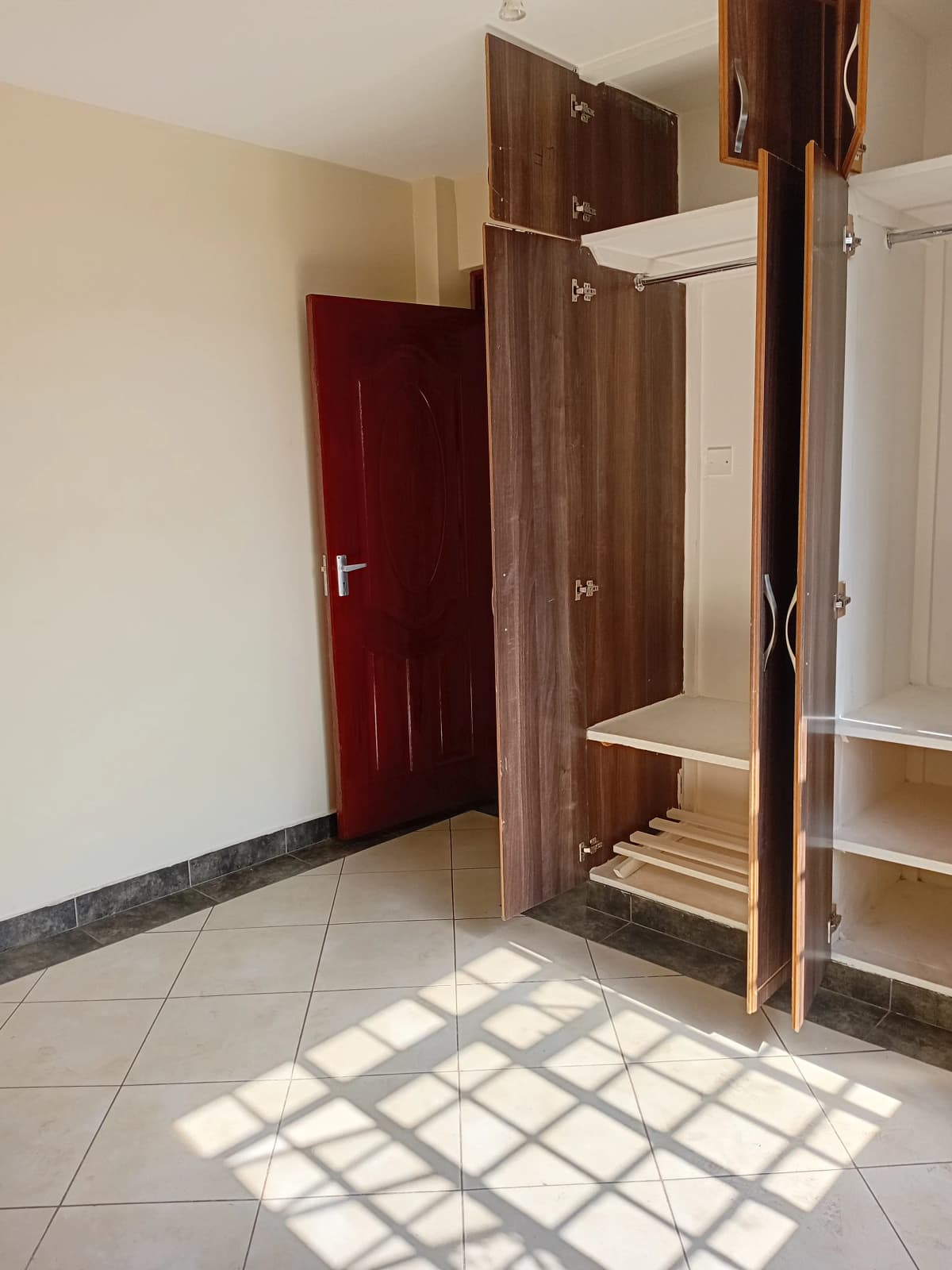 Unfurnished bedroom with wooden wardrobe and red door