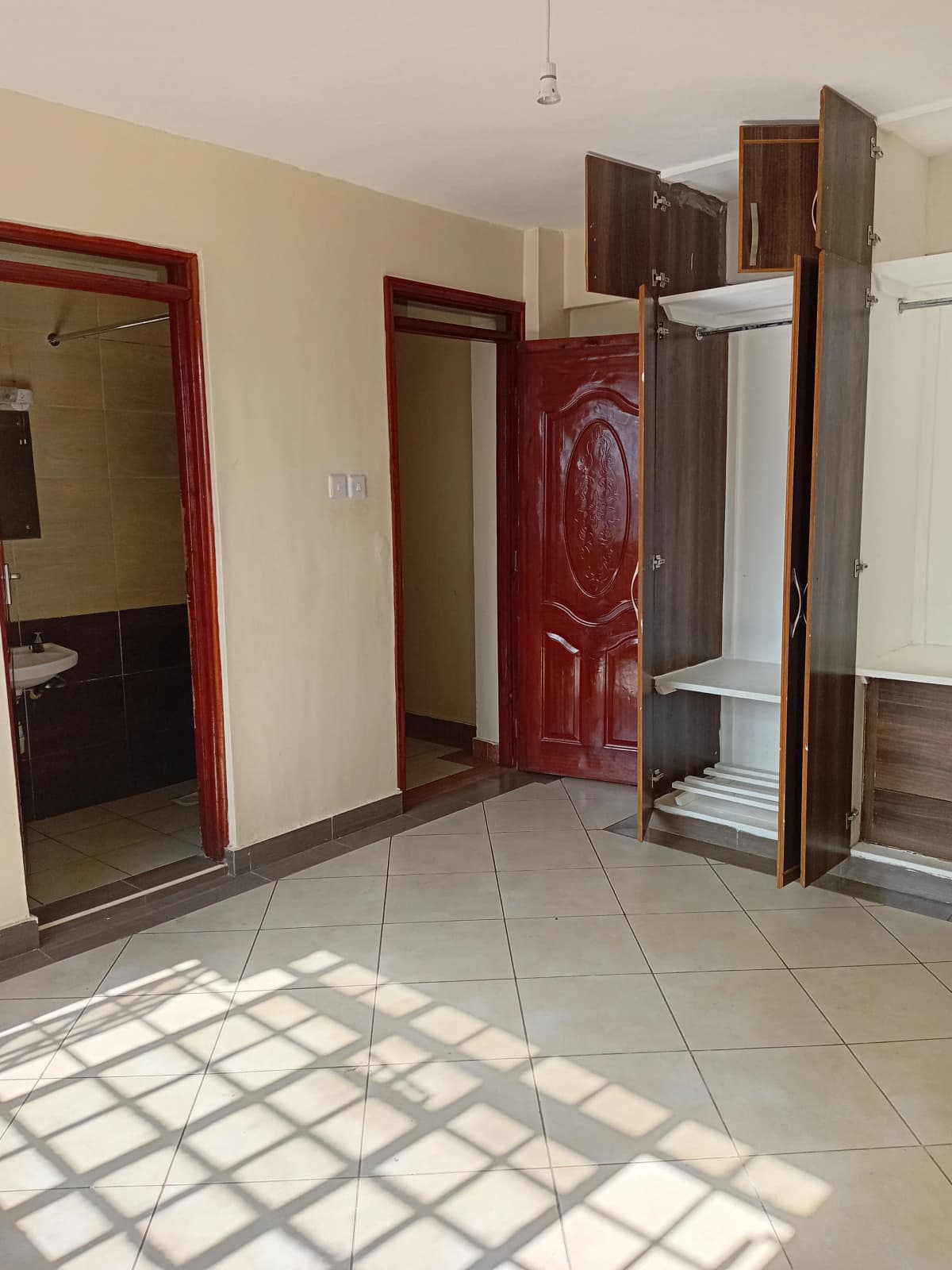 Bright corridor with tiled floor and multiple red wooden doors