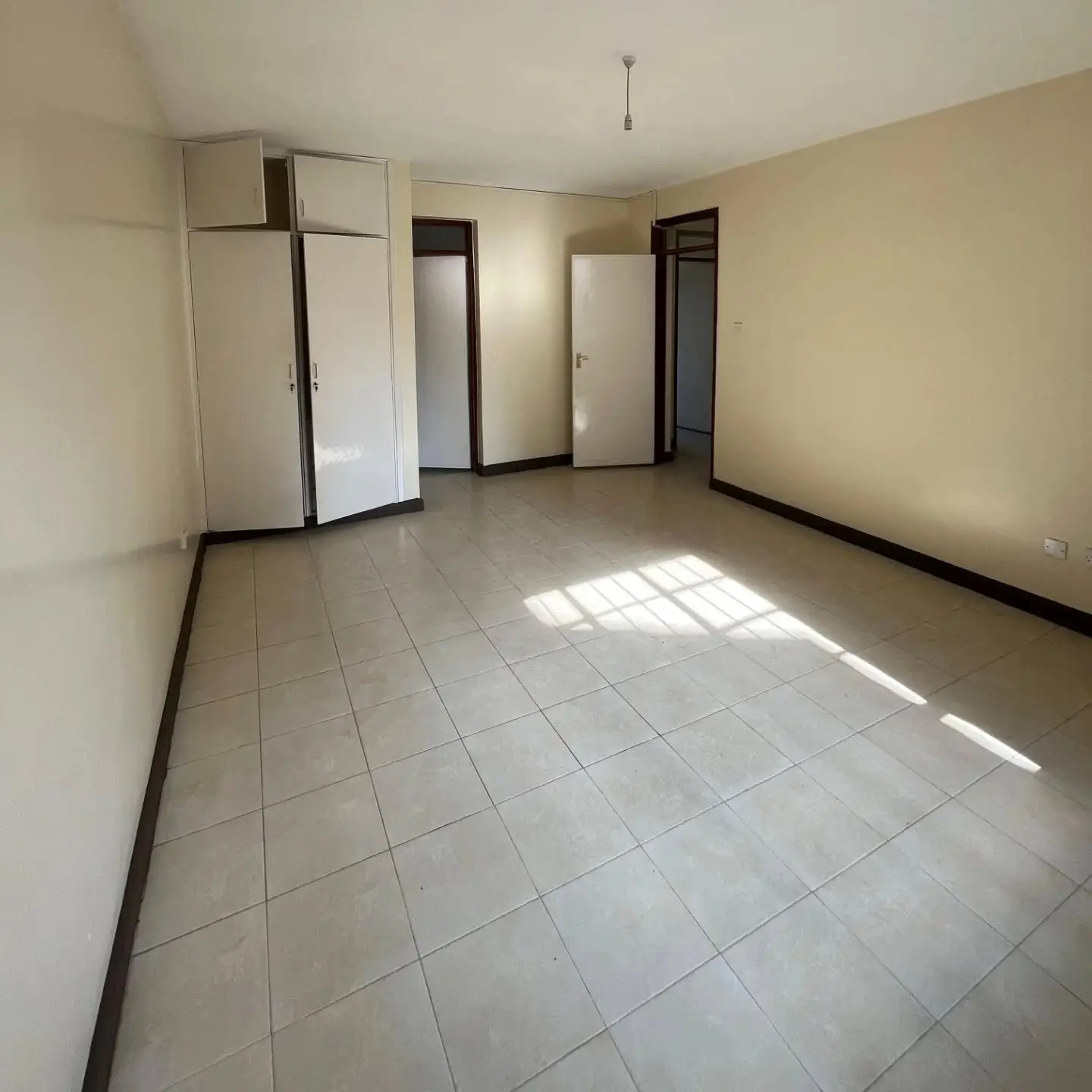 Empty bedroom with tiled floor and built-in wardrobes