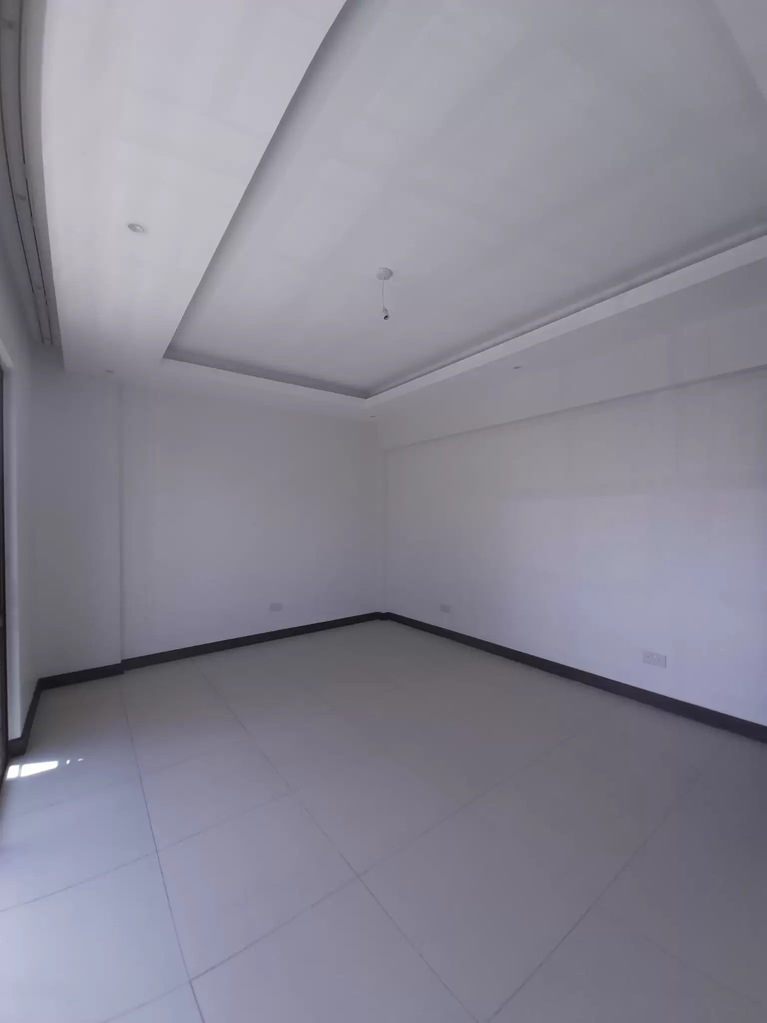 Empty bedroom with recessed ceiling and tile flooring