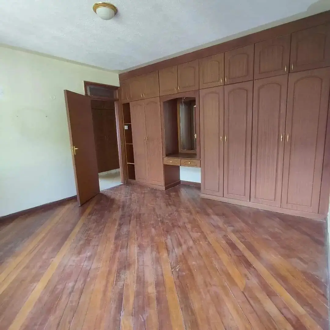 Spacious bedroom with built-in wooden wardrobes and hardwood flooring