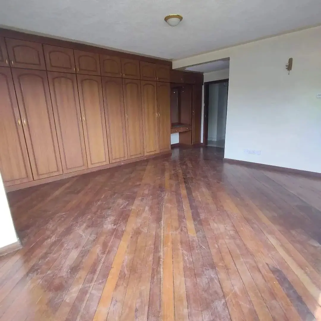 Spacious bedroom with wooden wardrobe and polished wood flooring