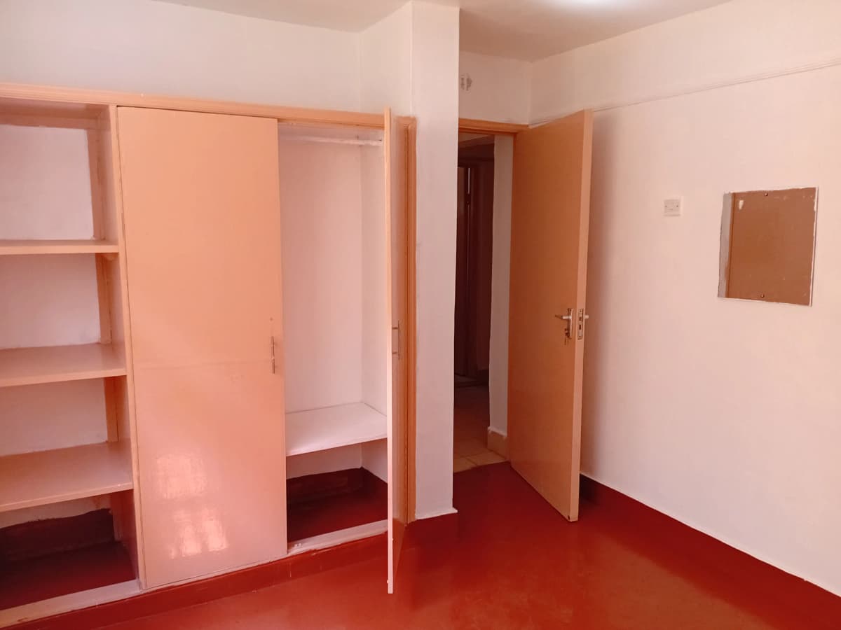 Spacious bedroom with built-in wardrobe and red flooring
