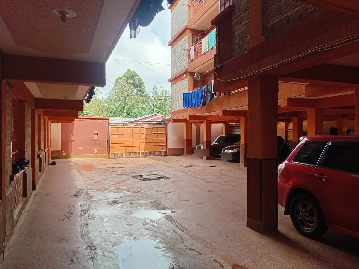 Covered parking bay with red vehicle, wet ground