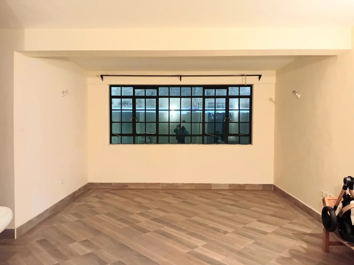 Bright living room with large gridded window and wooden flooring