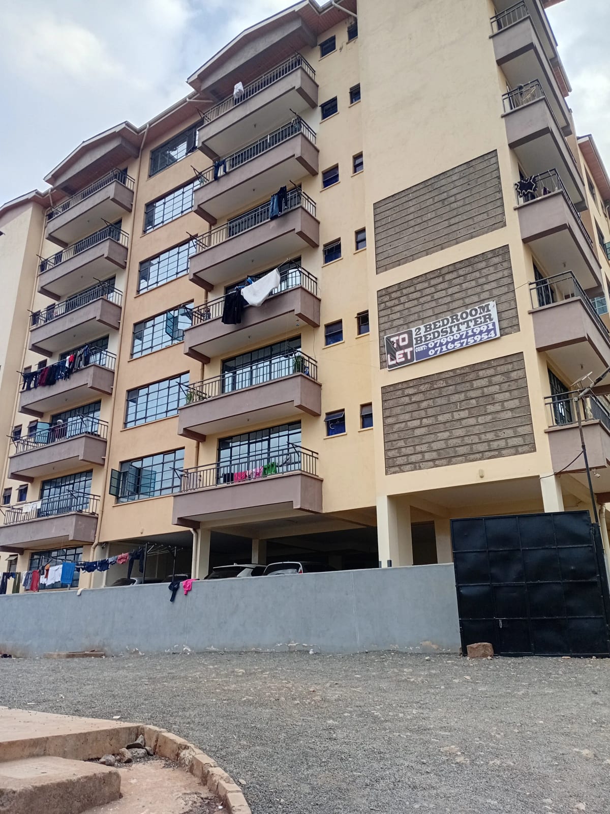 Multi-story residential building facade with balconies and ground parking