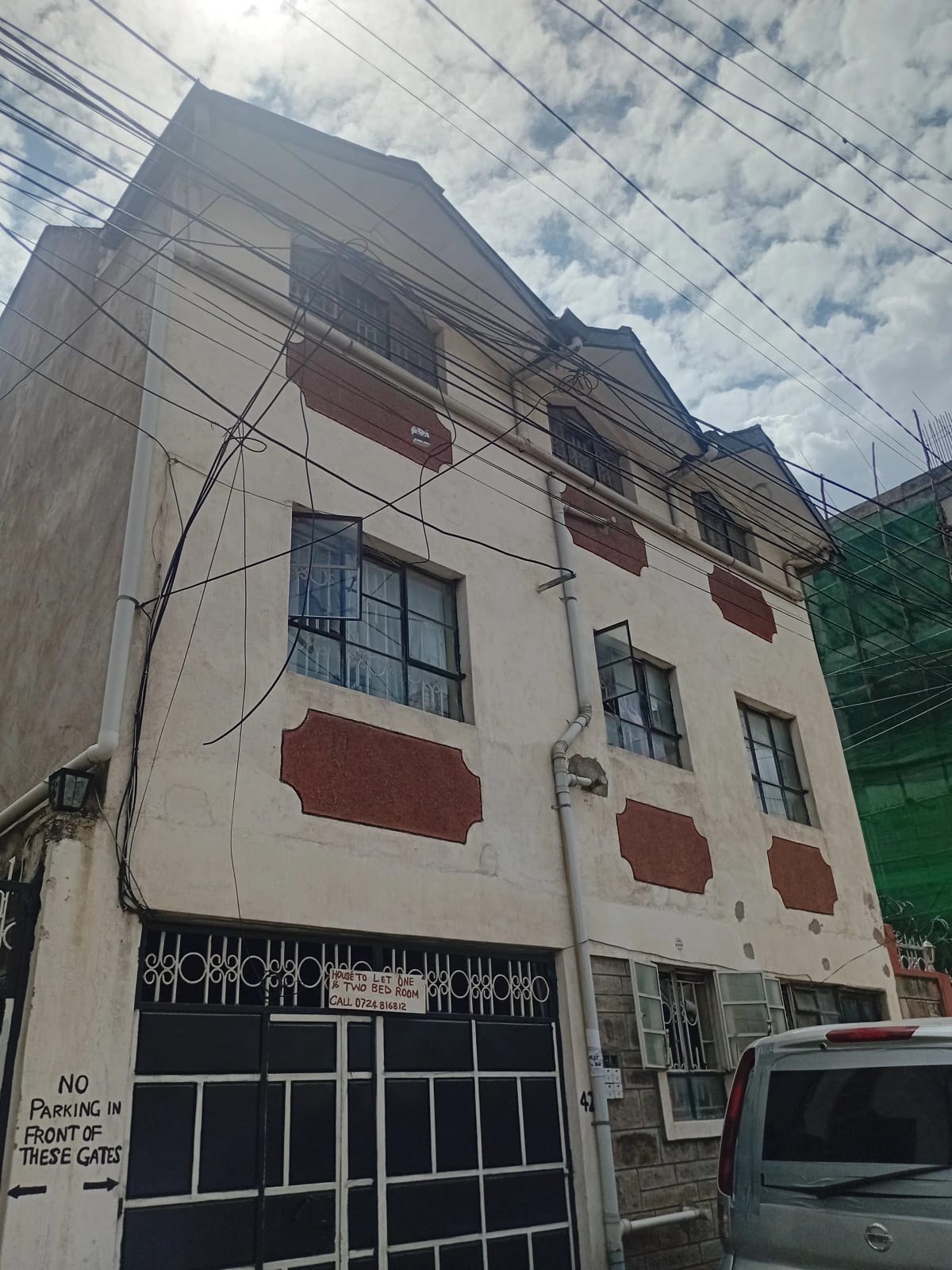 Multi-story residential building facade with red window shutters