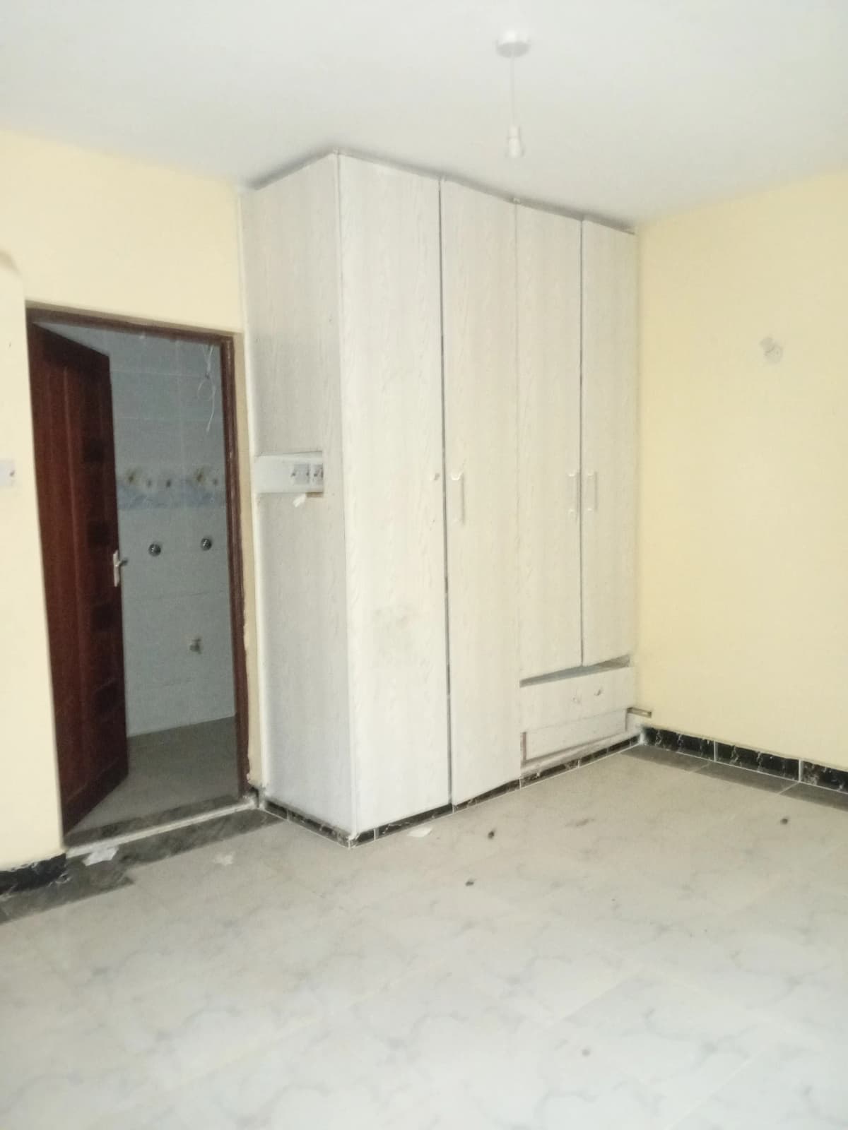 Unfurnished bedroom with large built-in wardrobe, cream walls