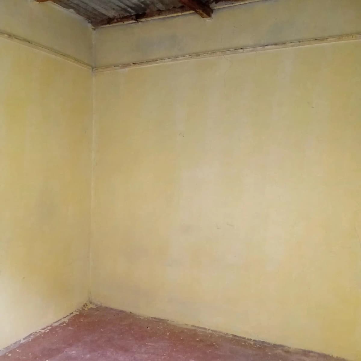 Empty bedroom with yellow walls and reddish floor