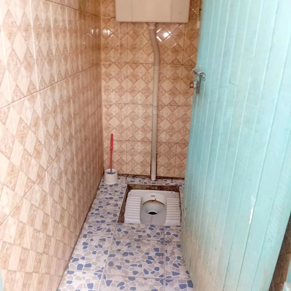 Compact bathroom with squat toilet and tiled walls