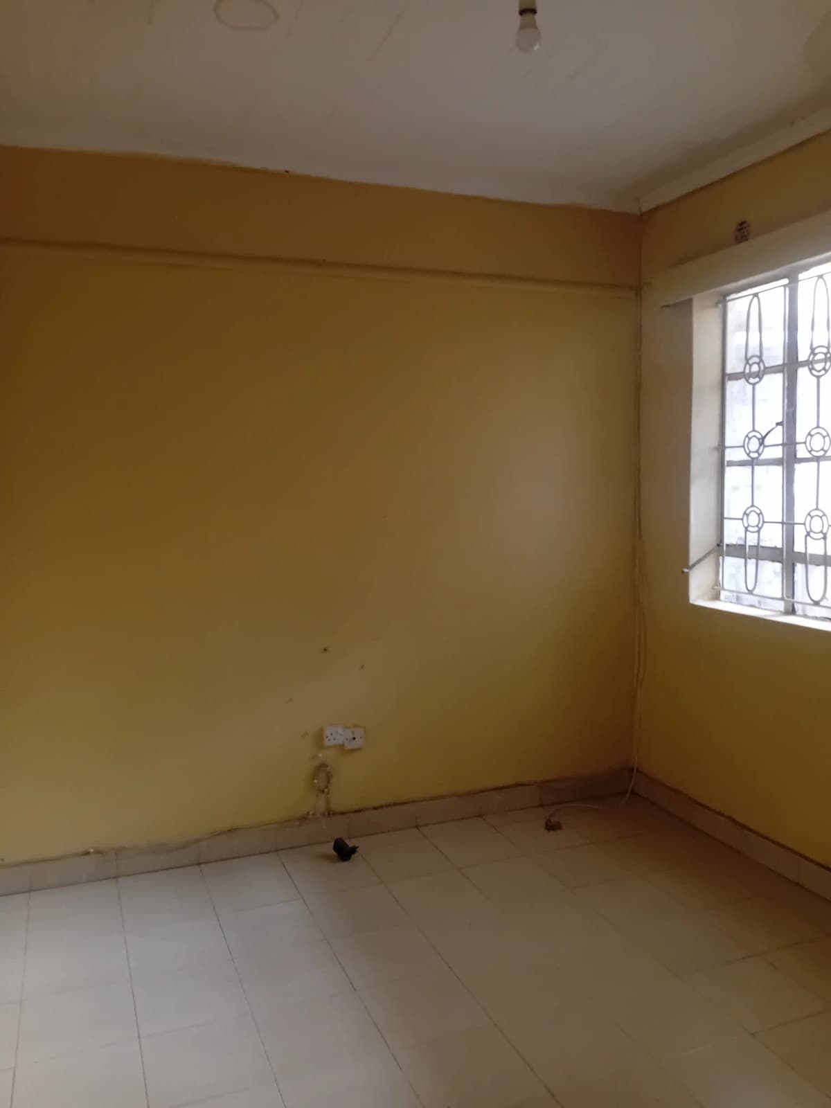 Empty bedroom with yellow walls and barred window