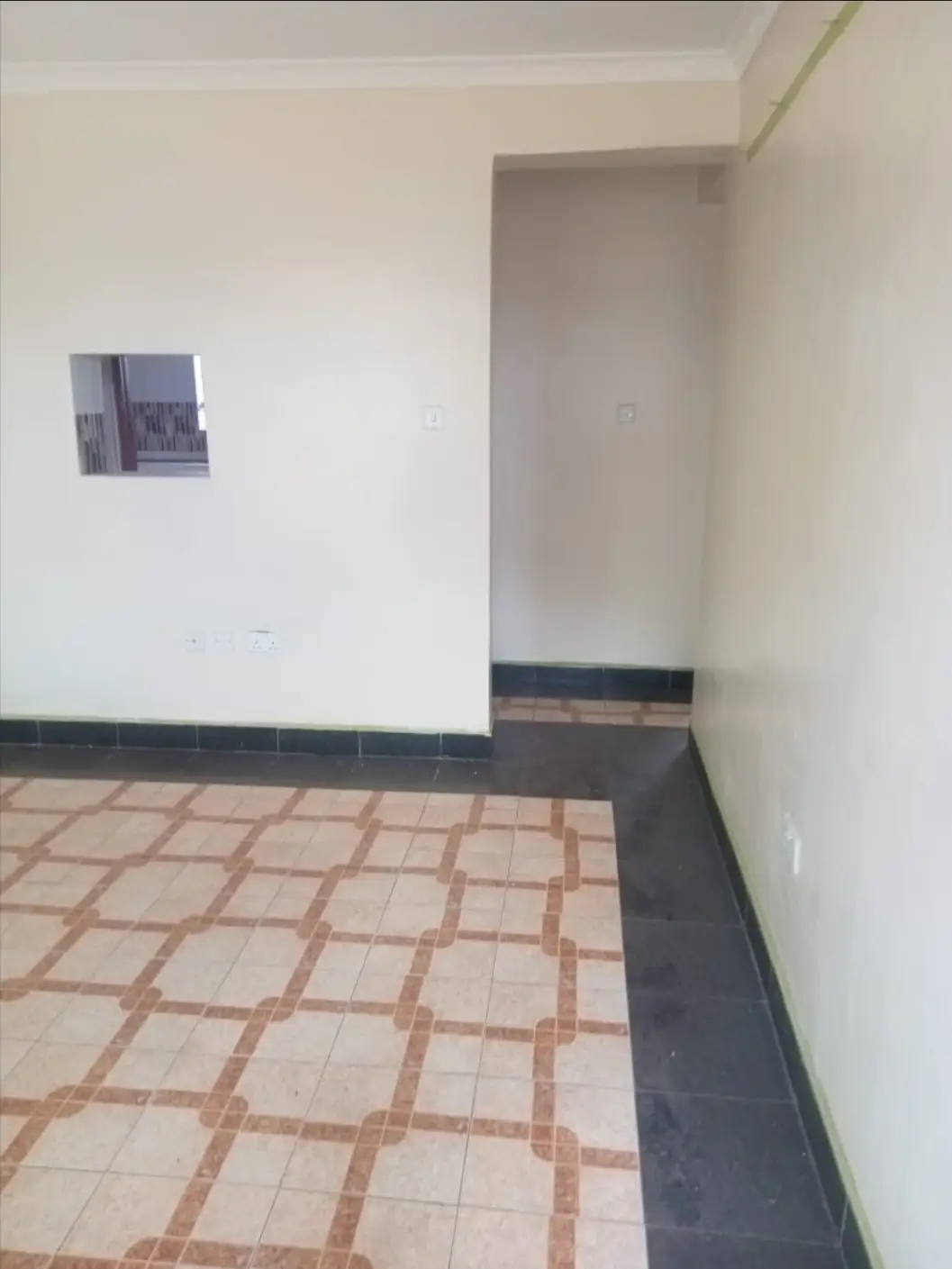 Empty corridor with terracotta tile flooring and white walls