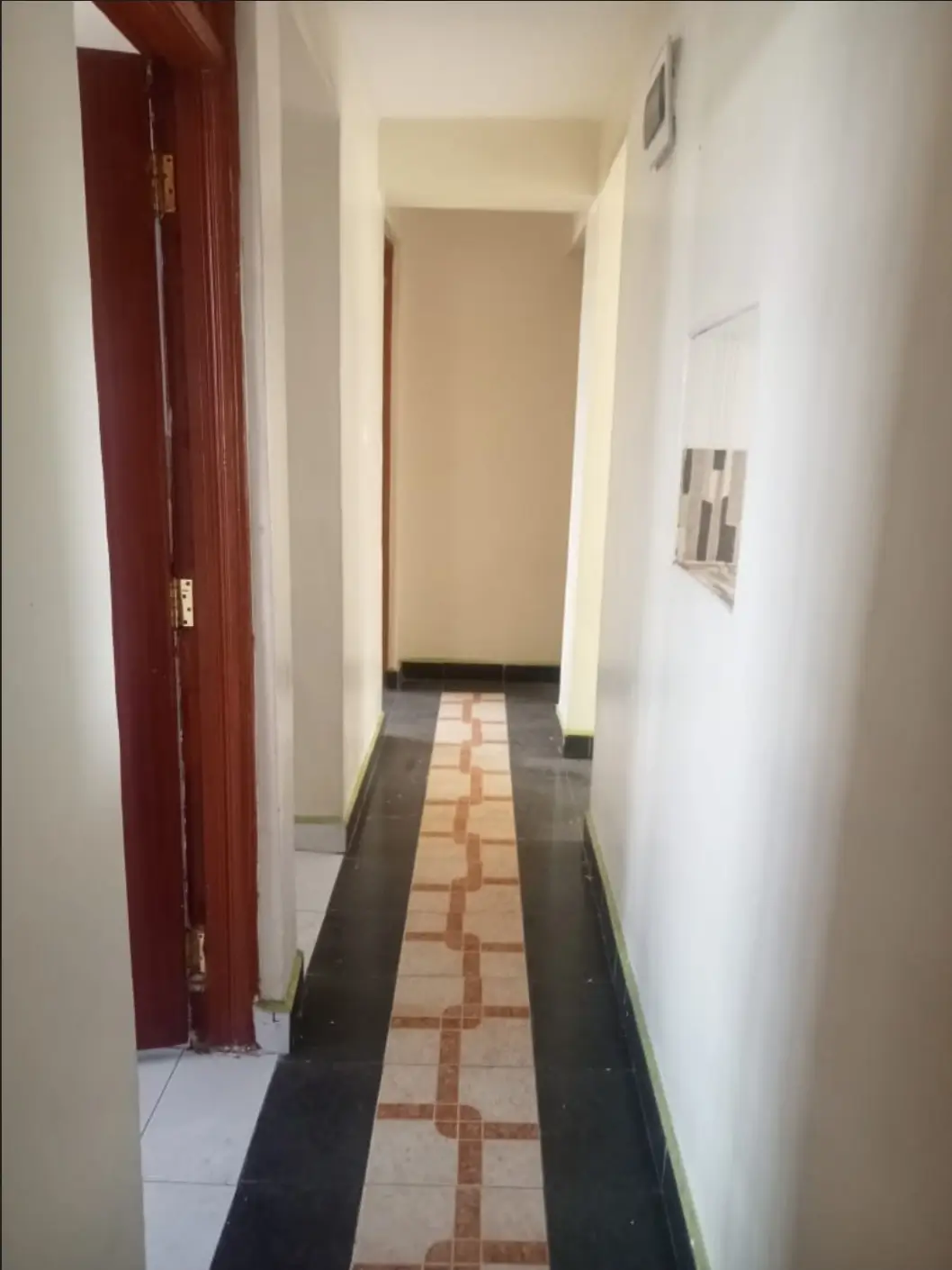 Narrow hallway with geometric tile flooring and white walls