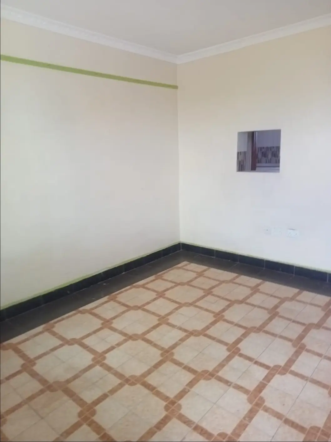 Empty bedroom with terracotta tile flooring and plain walls