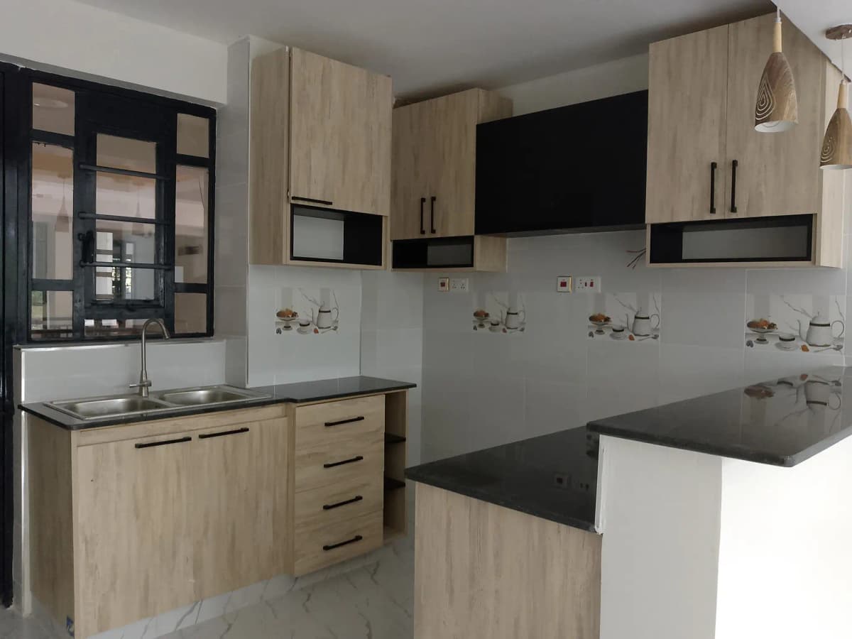 Modern kitchen with light wood cabinets and black countertops