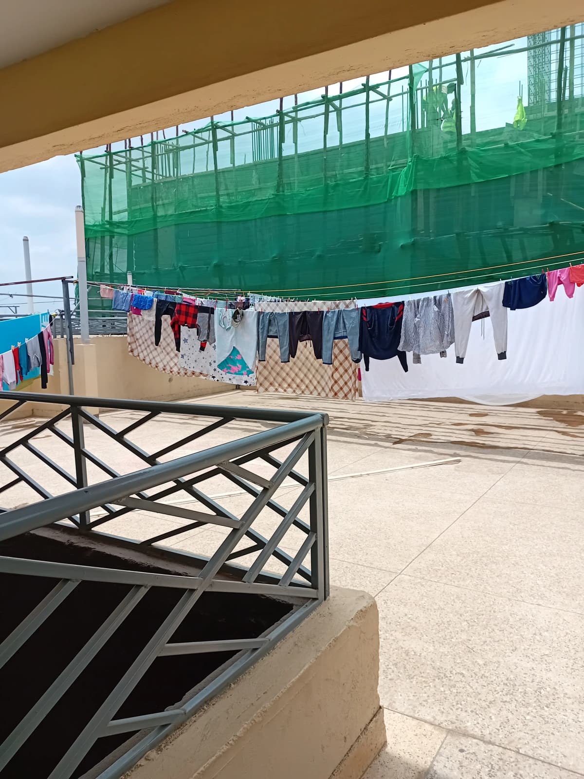 Rooftop laundry drying area with green shade netting