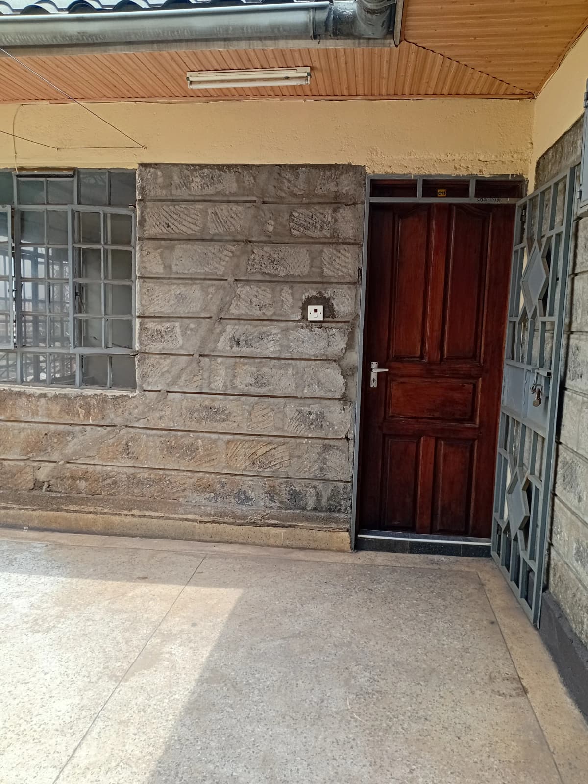 Property entrance with red door and concrete compound