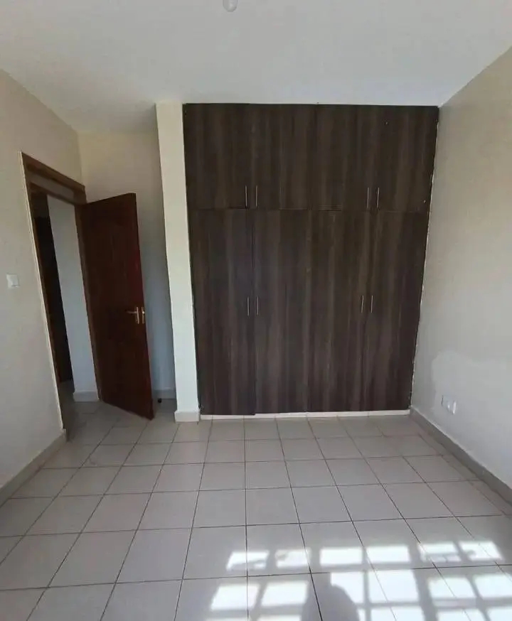 Spacious bedroom with built-in dark wardrobe, tiled flooring