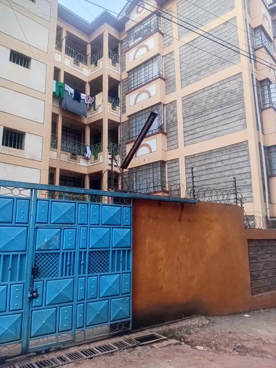 Multi-story residential building with blue metal gate entrance