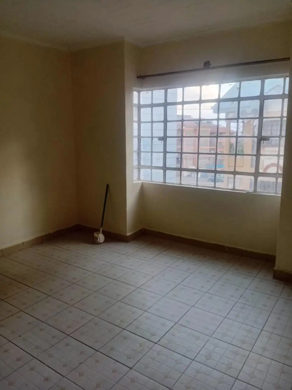 Unfurnished bedroom with large gridded window and tile flooring
