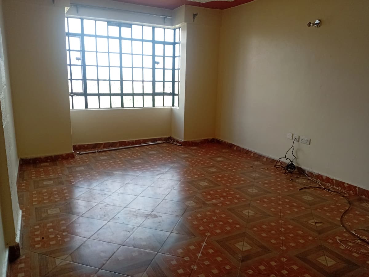 Empty living room with terracotta tile flooring and barred window