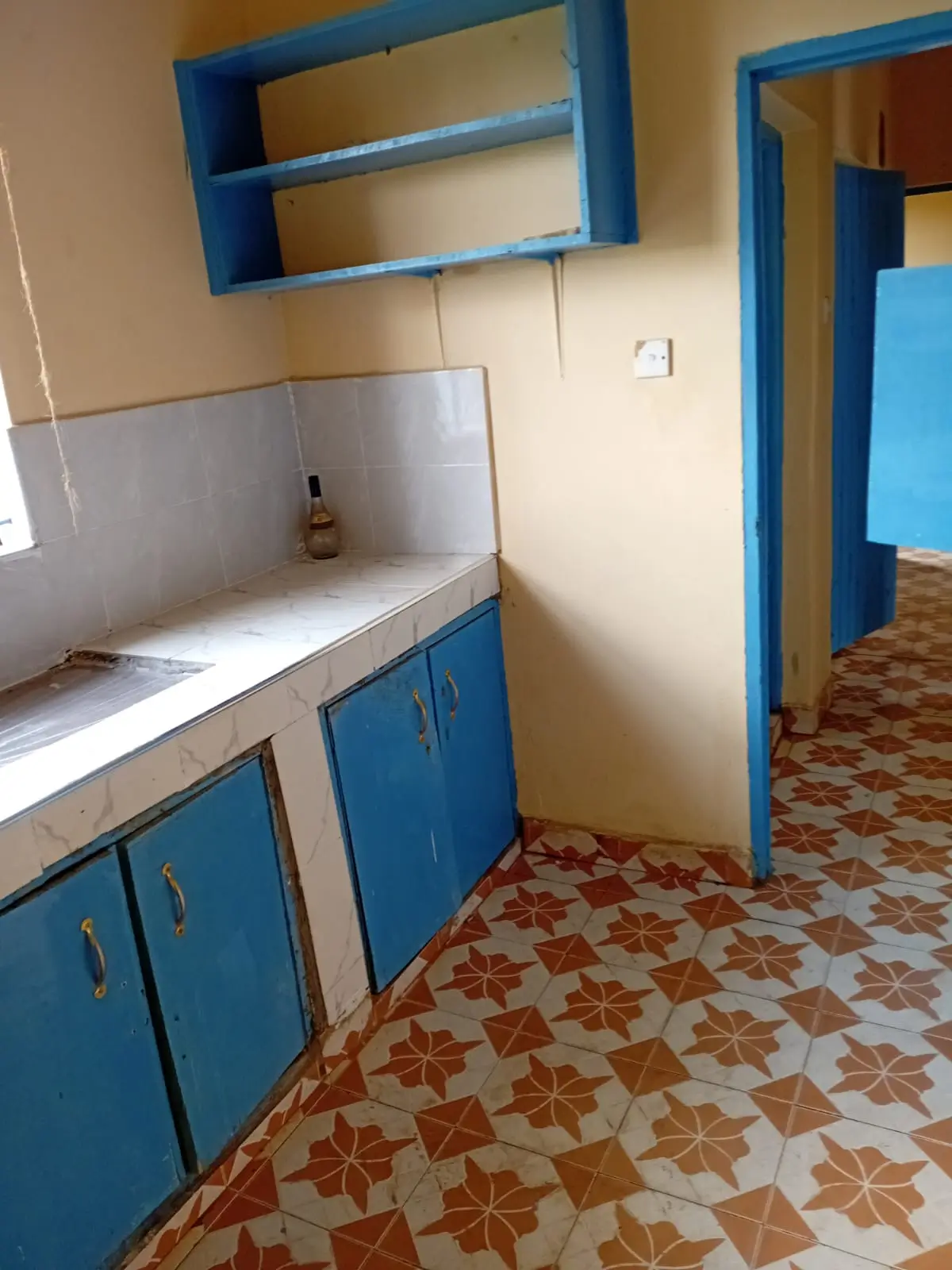 Blue kitchen cabinets with white countertop and overhead shelving