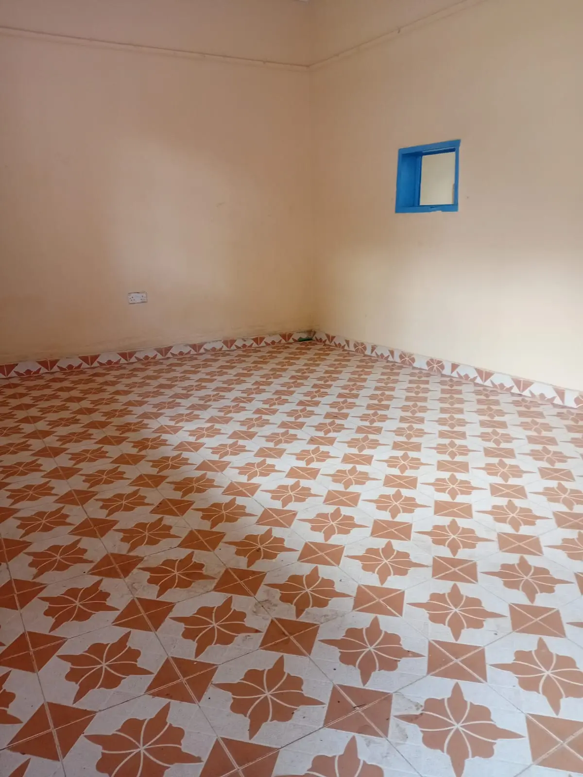 Empty bedroom with geometric terracotta tile flooring.