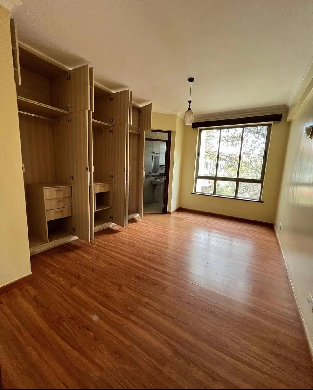 Spacious bedroom with built-in wooden wardrobes and natural light
