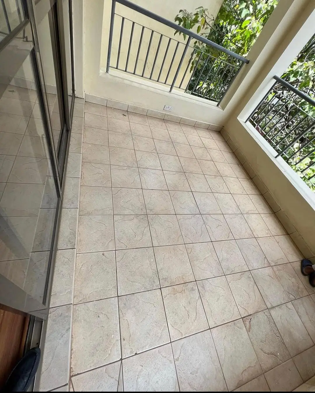 Spacious tiled balcony with metal railings and green views