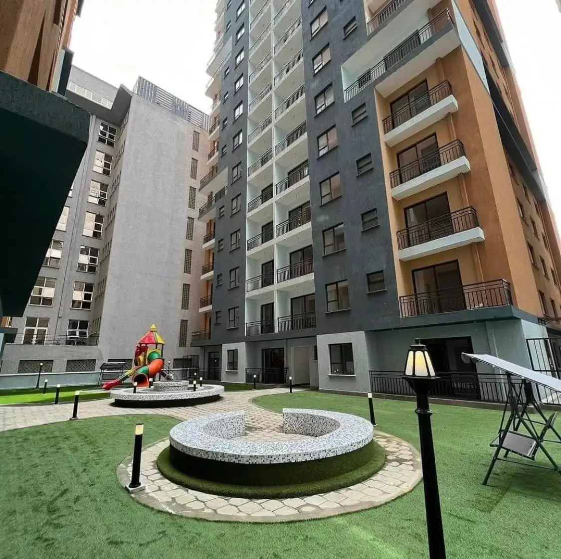 Landscaped compound courtyard with circular seating areas and multi-story buildings