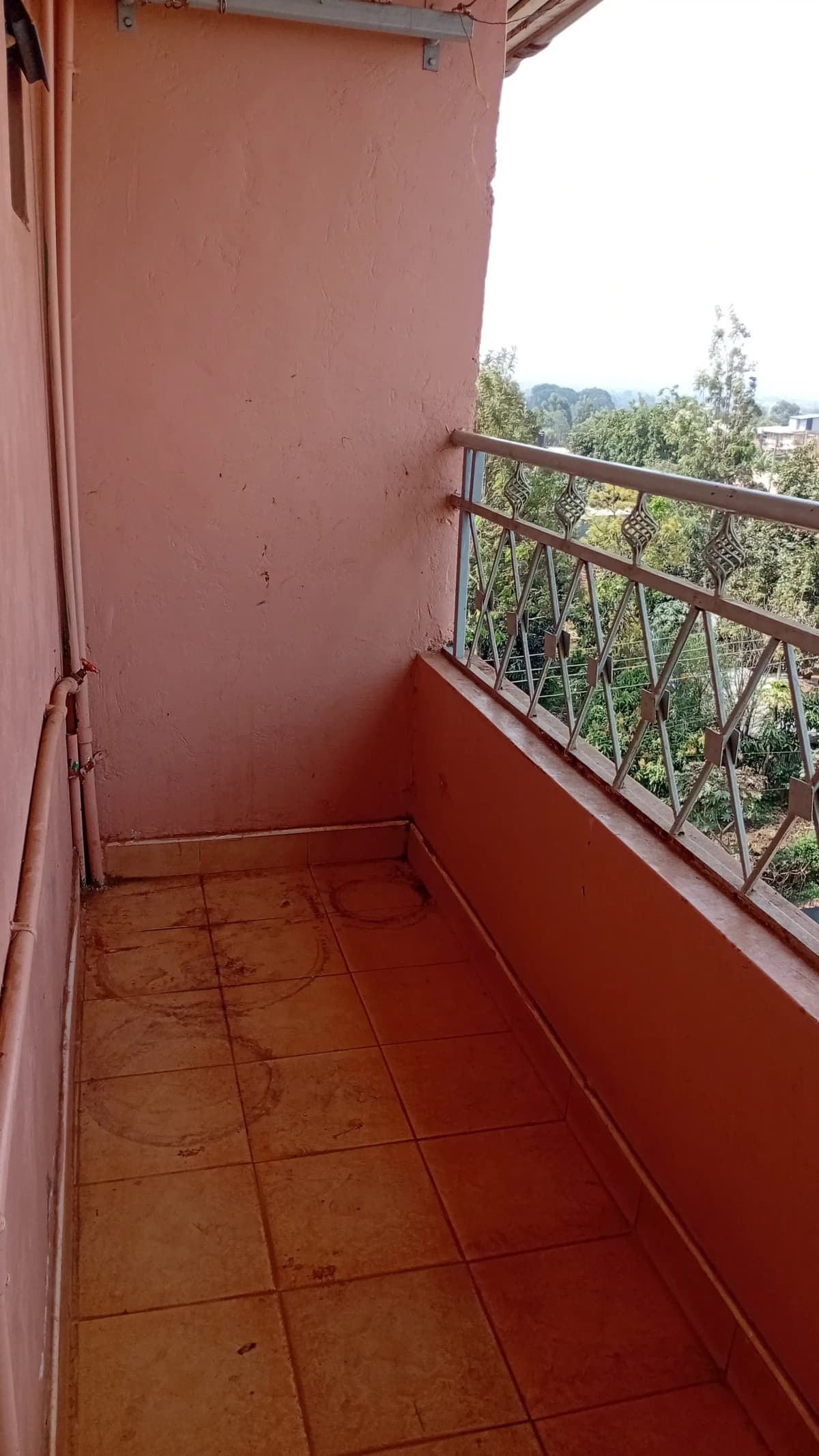 Spacious terracotta-tiled balcony with metal railing and valley views