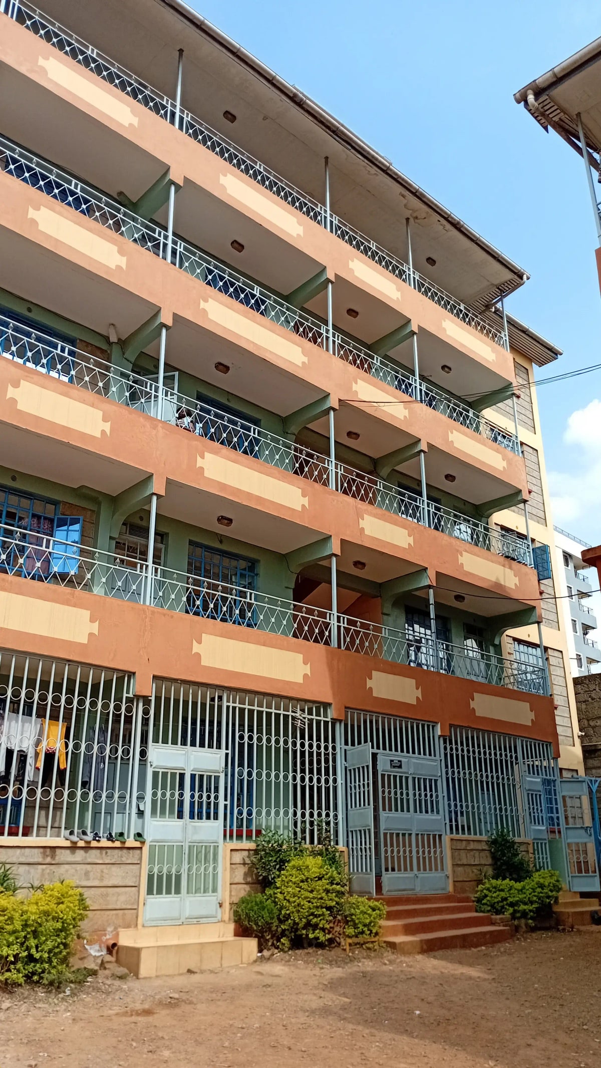 Multi-story residential building facade with balconies and compound entrance
