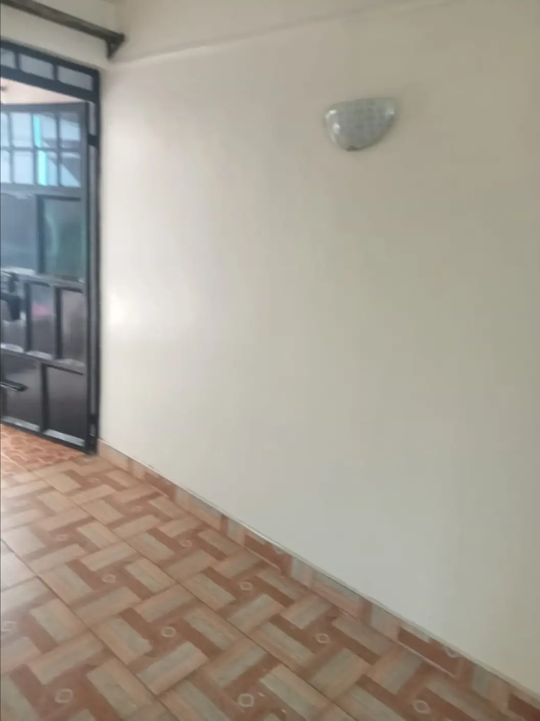 Empty corridor with herringbone tile flooring and glass door