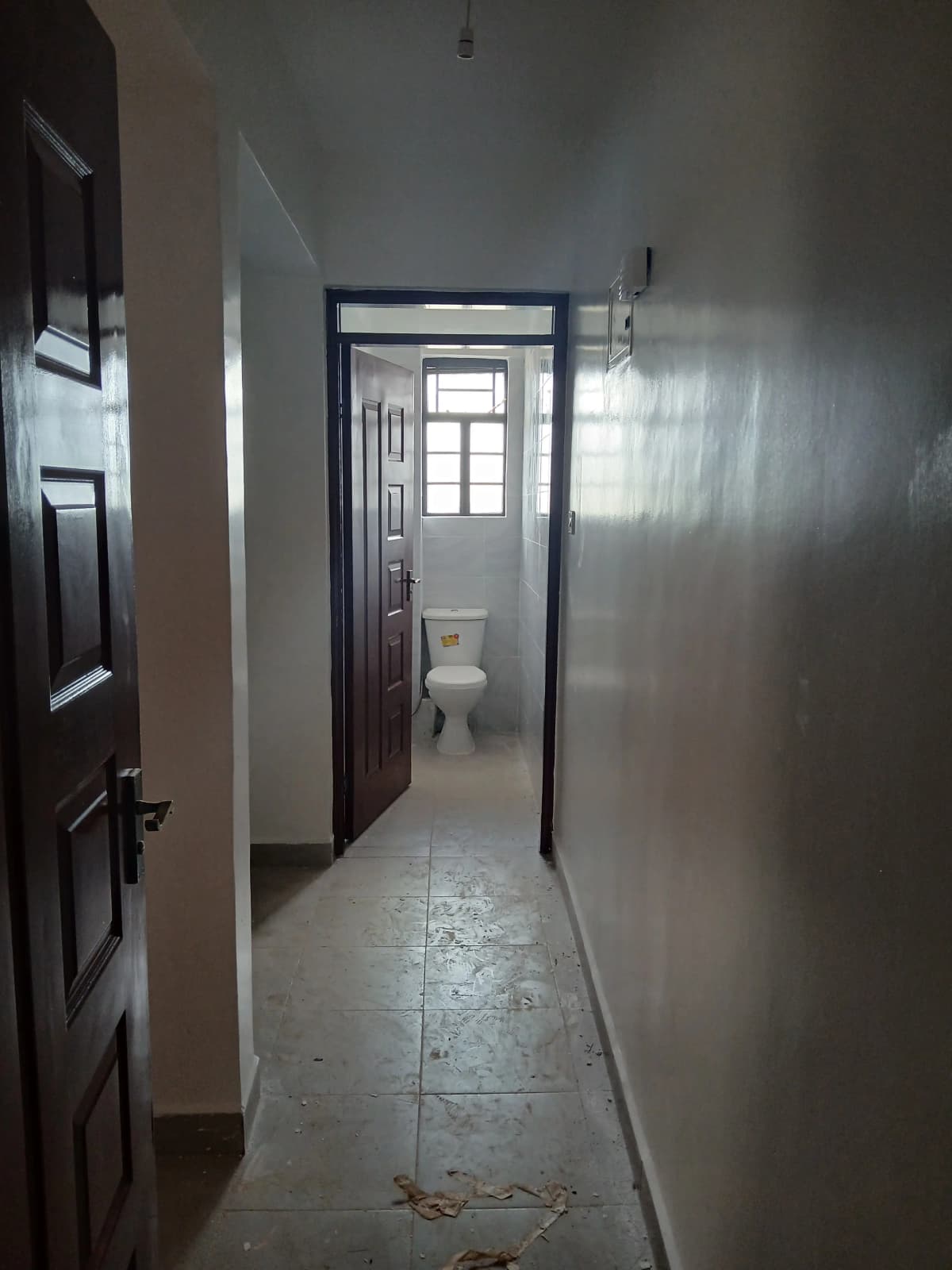 Narrow hallway corridor with toilet access, concrete flooring