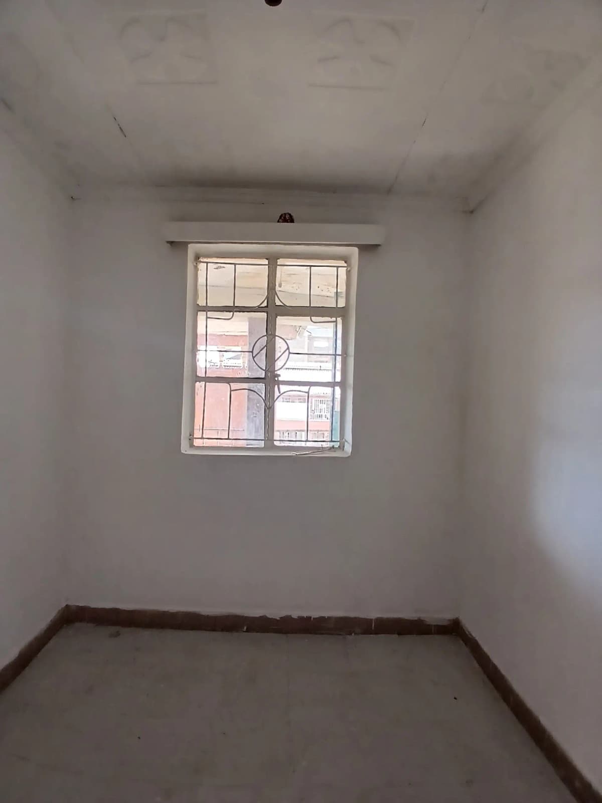 Bare bedroom with single window and wooden floor trim