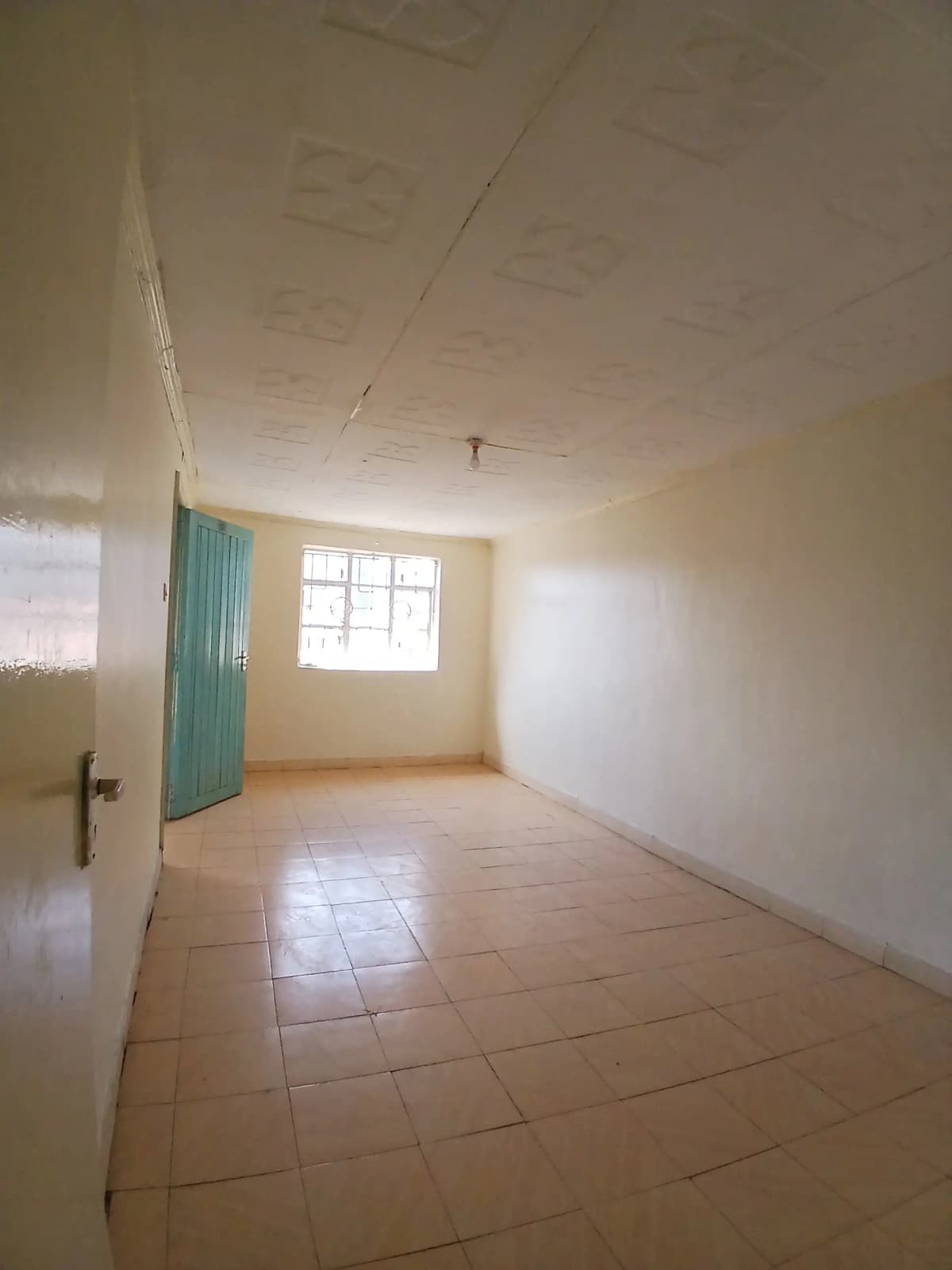Spacious empty bedroom with tiled flooring and natural light
