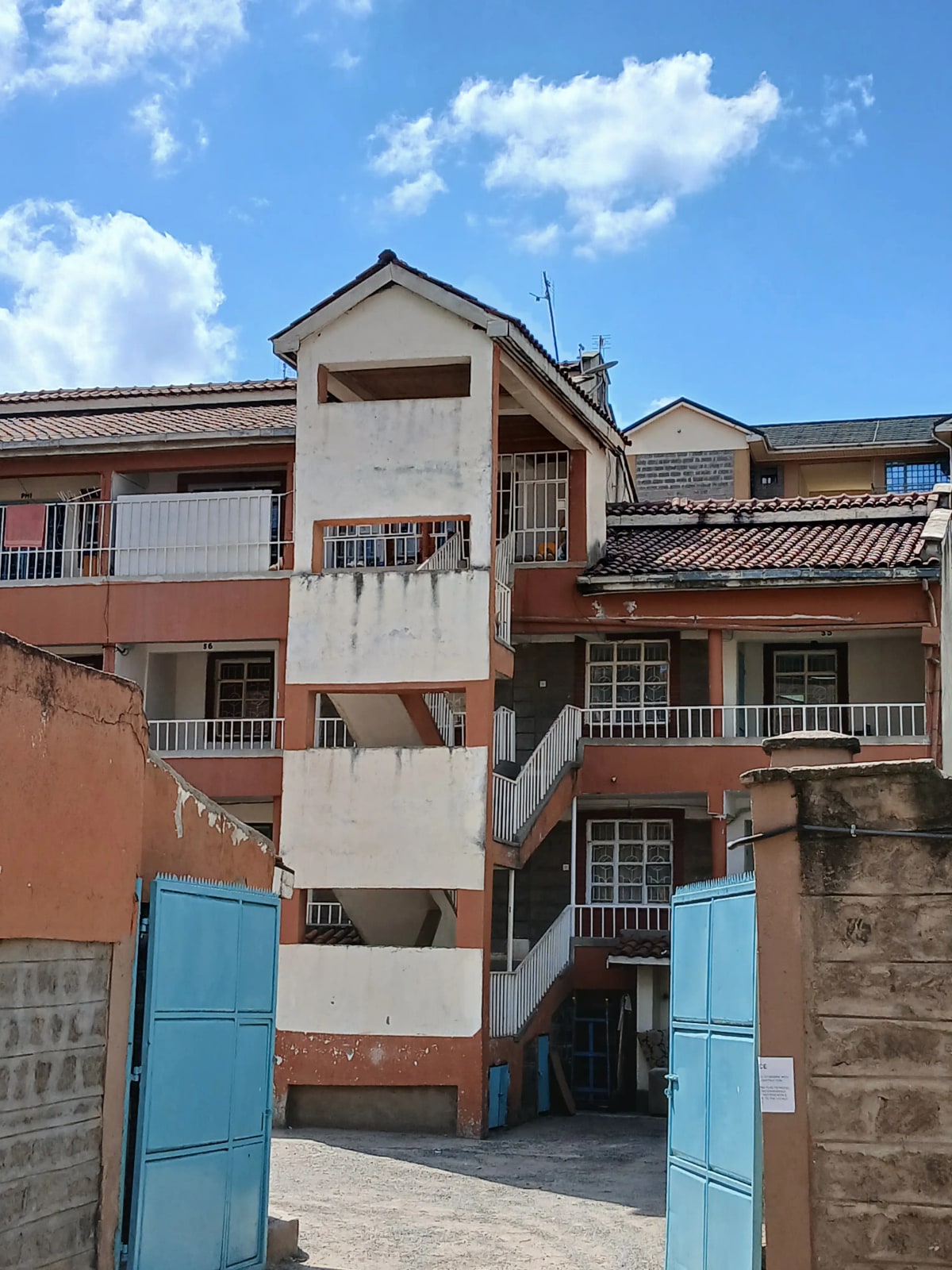 Multi-story residential building facade with blue gates entrance