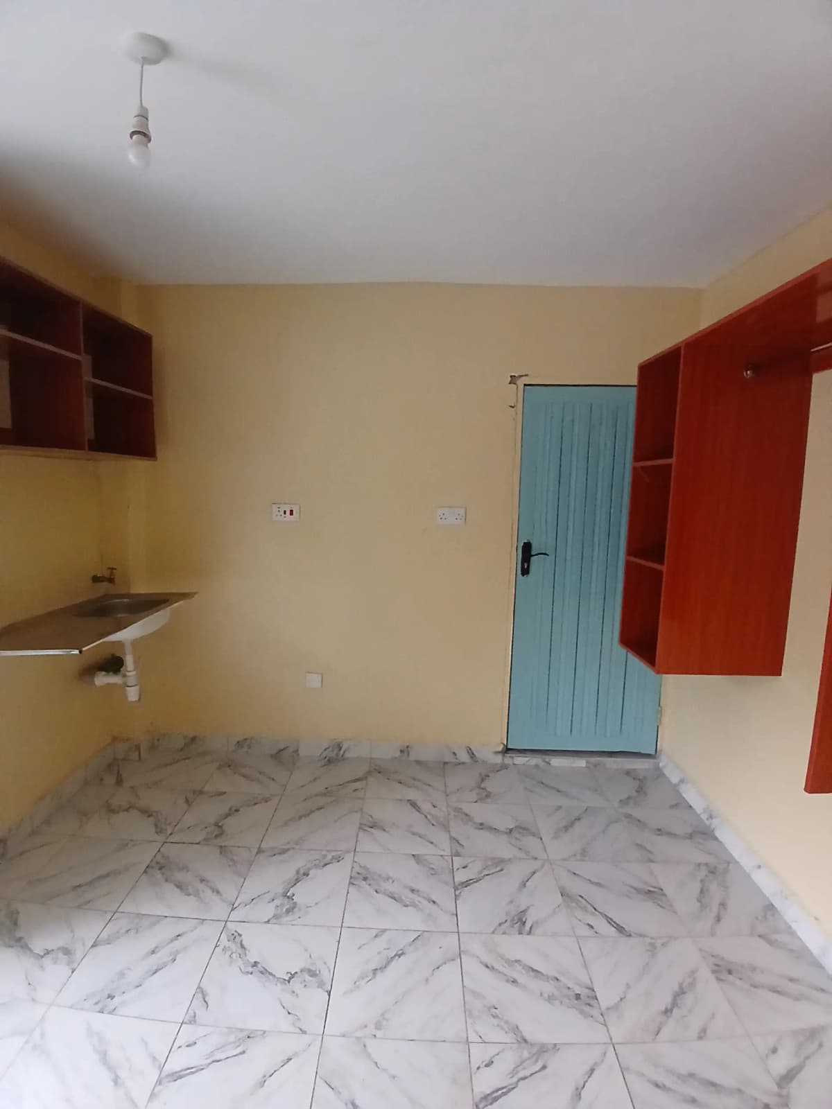 Compact bedroom with integrated kitchenette and patterned tile flooring