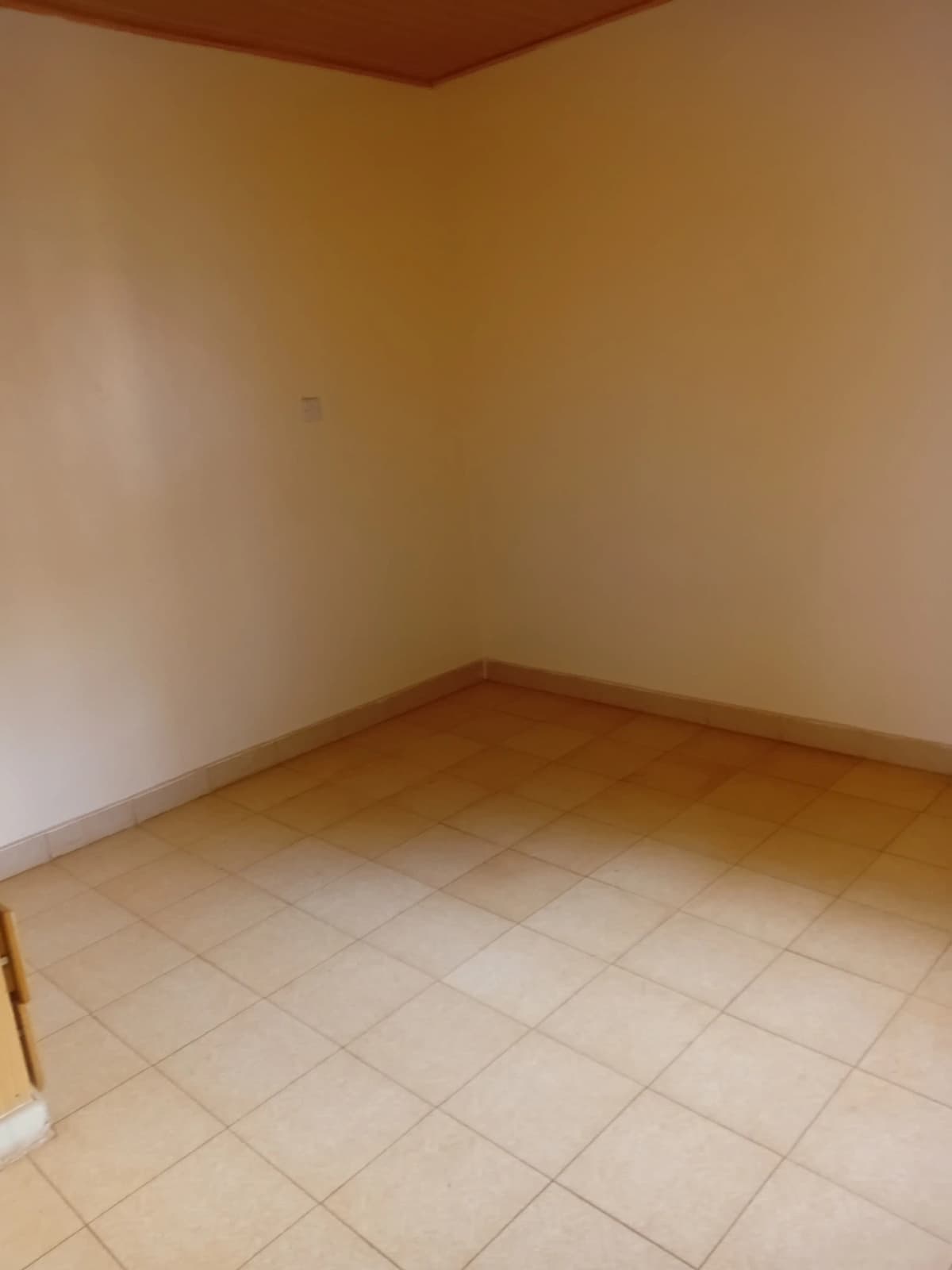Empty bedroom with cream tiled floor and brown ceiling