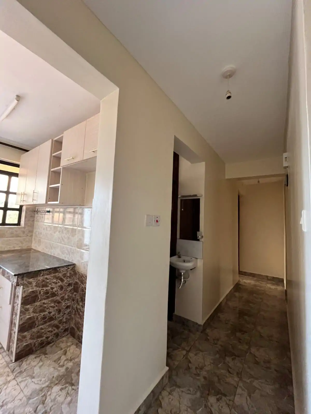 Corridor with kitchen visible on left, neutral tile flooring