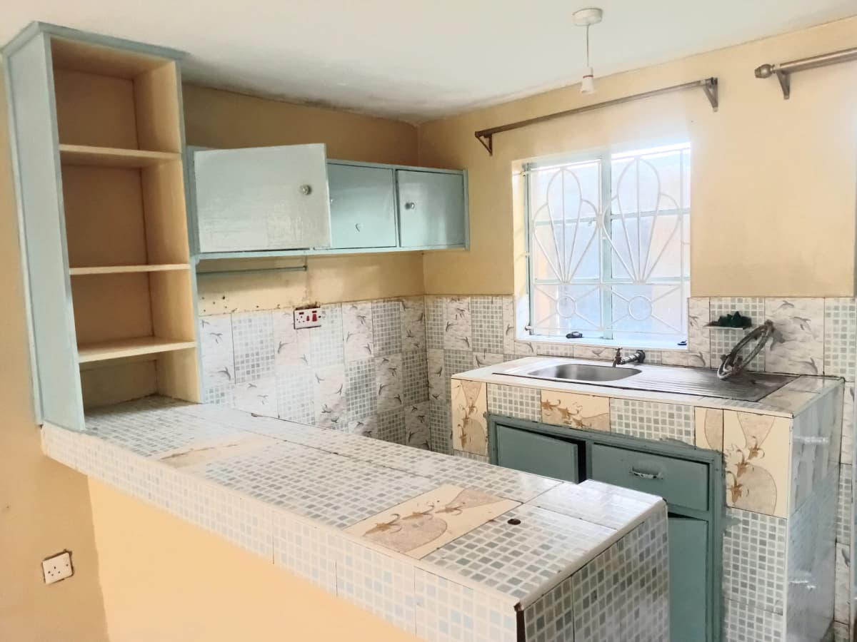 Compact kitchen with white tile backsplash and green cabinetry